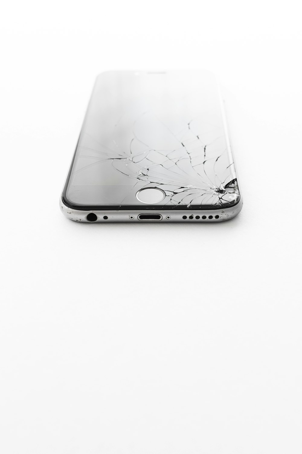 Celular con el vidrio trizado sobre fondo blanco