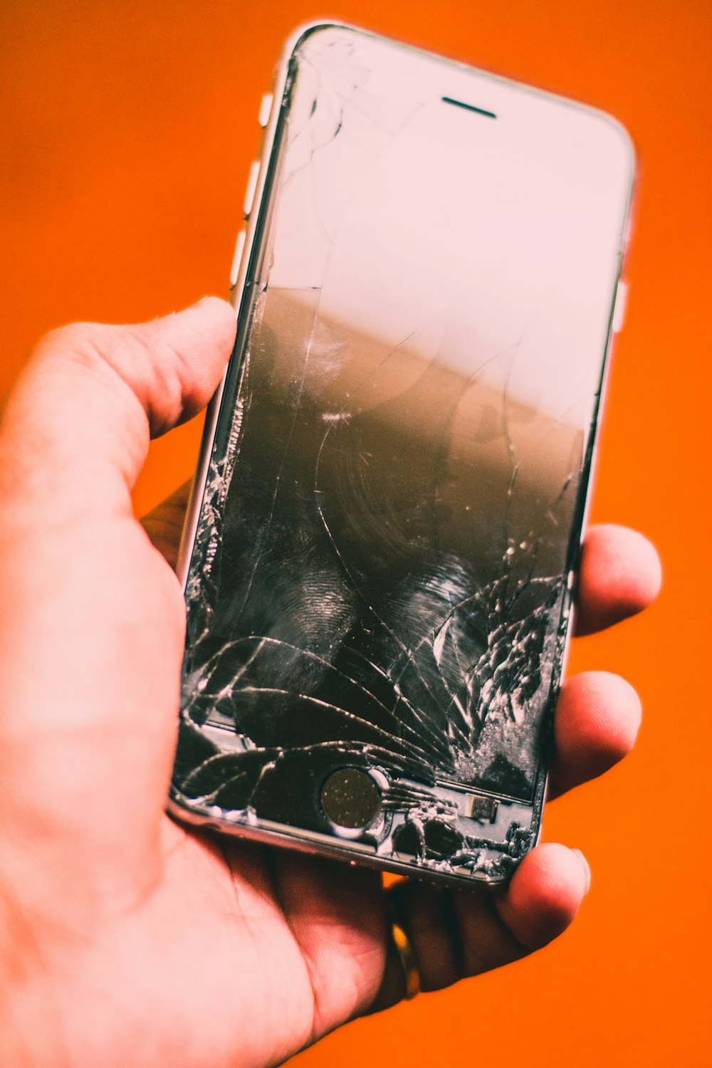 Mano sosteniendo un celular con la pantalla trizada